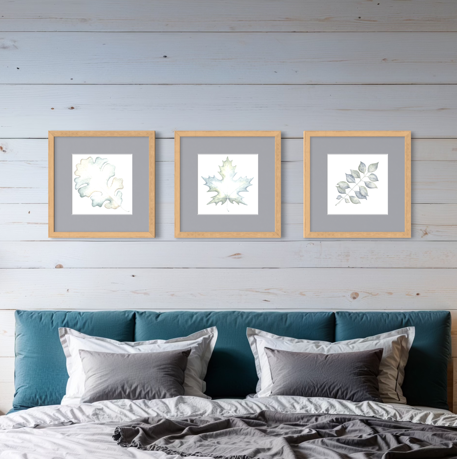 Framed artwork featuring colorful leaves on a wall above a bed with blue headboard and gray bedding.