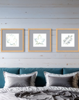 Framed artwork featuring colorful leaves on a wall above a bed with blue headboard and gray bedding.